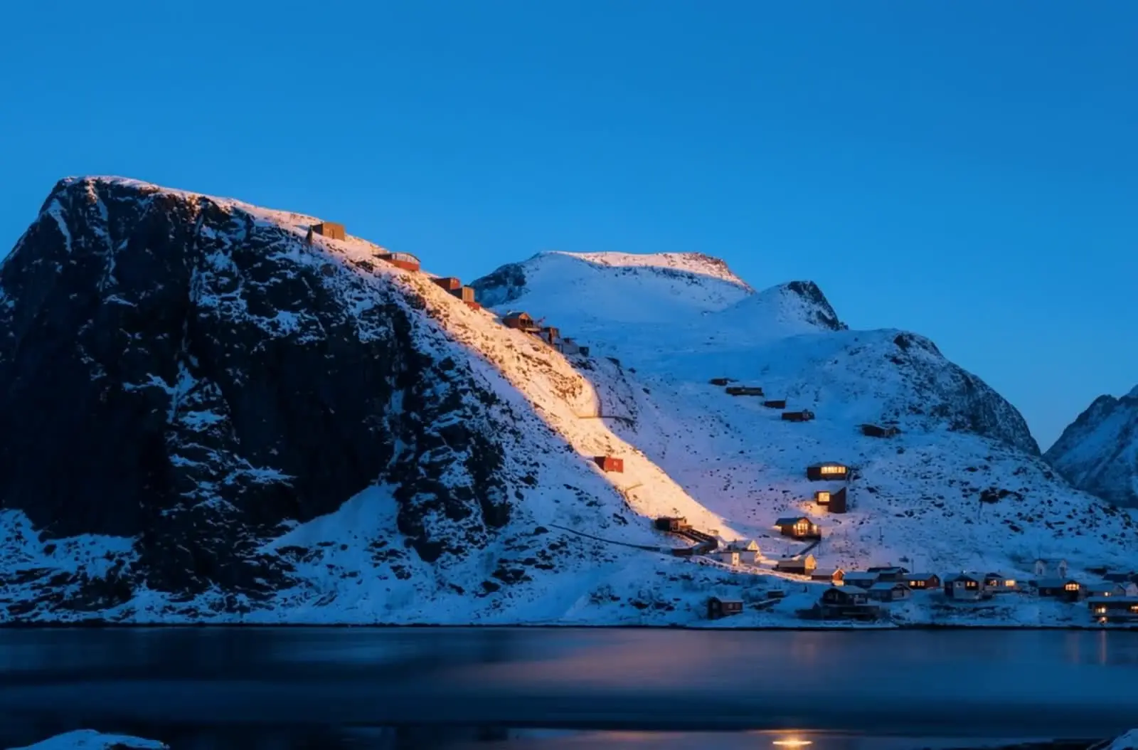 Vindstad at the head of Kjerkfjorden, Lofoten — timber structures reflected in still fjord water at dusk